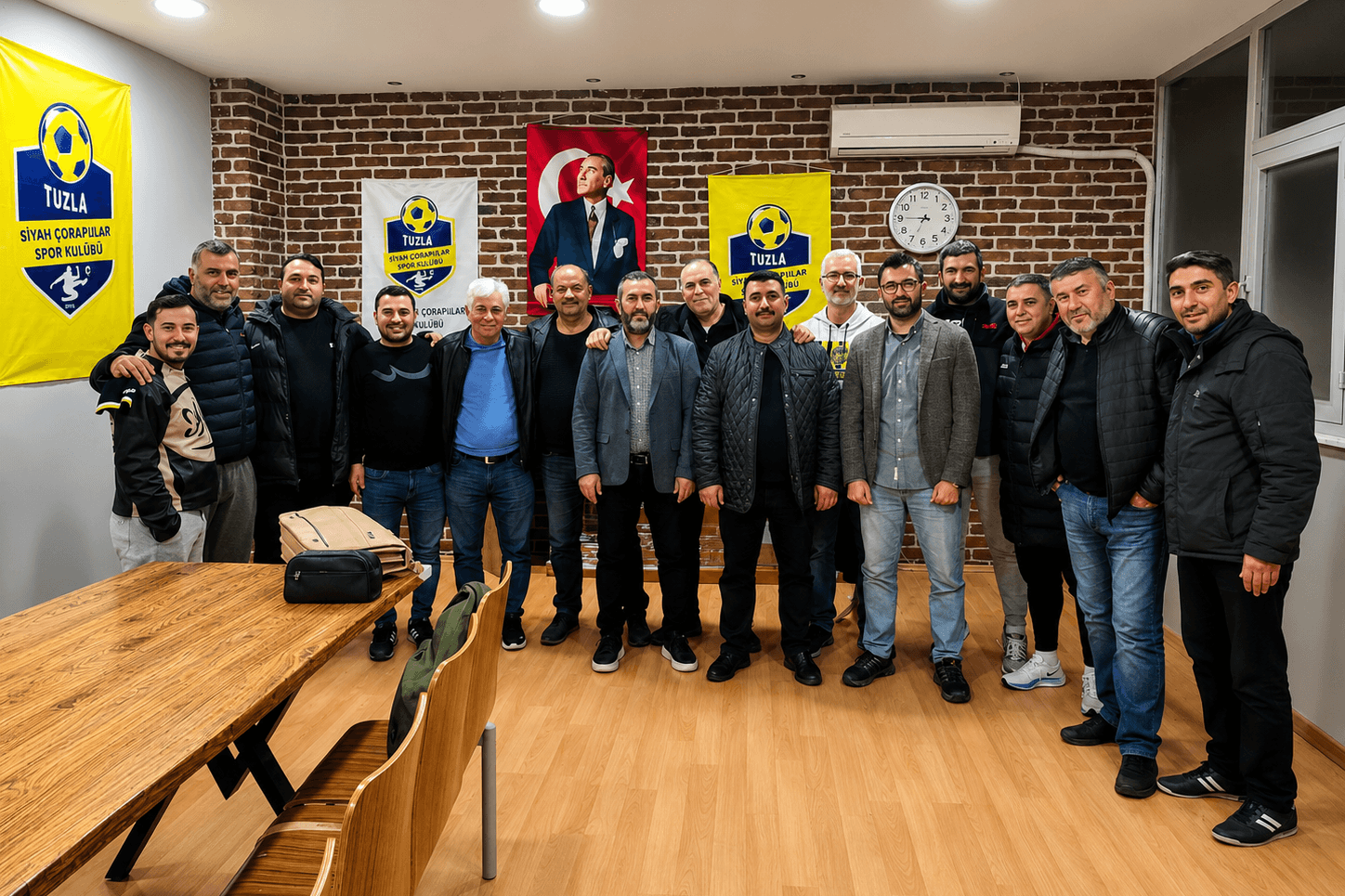 Tuzla Siyah Çoraplılar Spor Kulübü üyeleri kulüp lokalinde, kulüp flamaları ve Atatürk portresinin önünde topluca poz veriyor