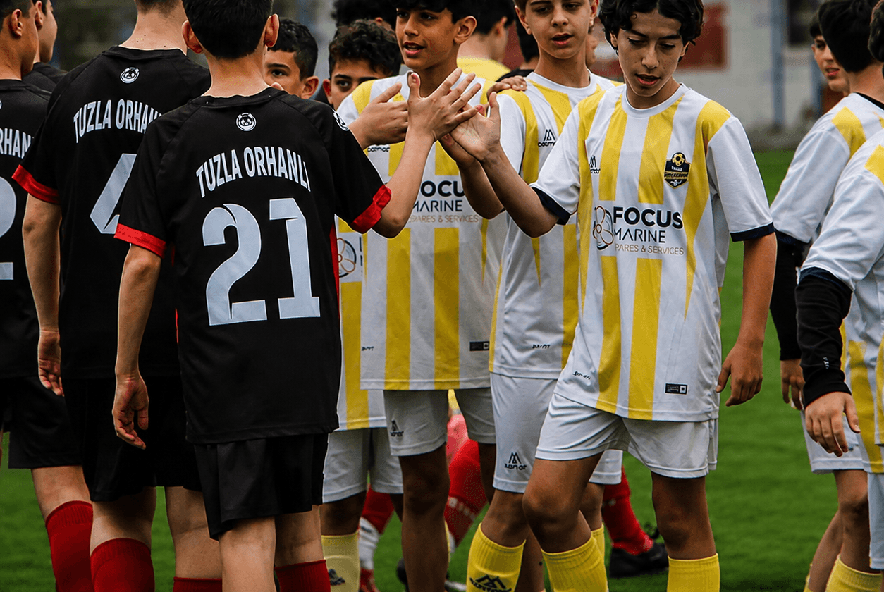 Maç öncesi sahada rakip takım oyuncularıyla tokalaşan sarı-beyaz formalı Tuzla Siyah Çoraplılar oyuncuları